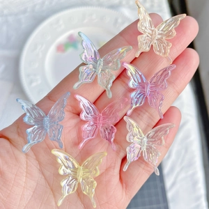 Macro shot of 7 colorful translucent baroque butterfly acrylic charms held in a hand