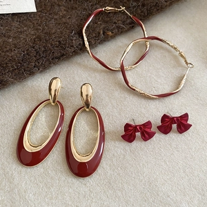 Detailed set of vintage gold and burgundy red earrings on soft knit background