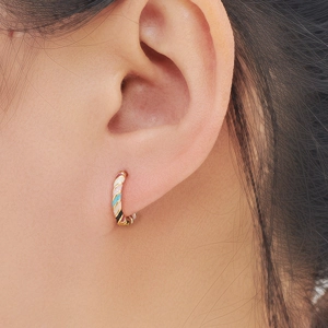 Rainbow enamel striped gold hoop earrings worn by model with vibrant spiral design