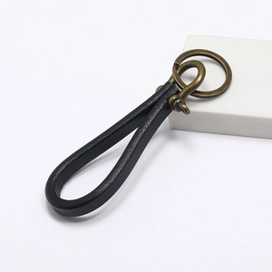 Handmade vintage black leather keychain with bronze horseshoe buckle on a white background