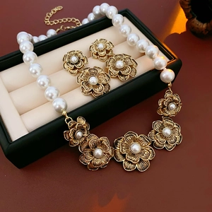 Detail shot of vintage golden flower necklace and pearl earrings in a luxury black jewelry box