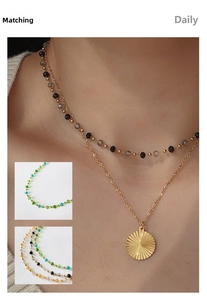 Close-up of double-layer gold necklace with colorful beads and sunburst sun pendant