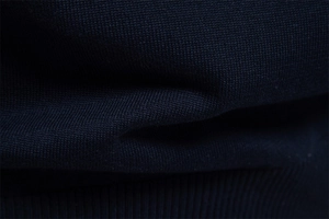 Detailed macro view of navy blue knitted cotton texture and ribbed hem on the V-neck sweater