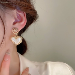 Close-up of vintage heart earrings with pearls and gold floral accents on model