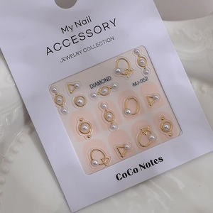 Macro detail of 3D pearl nail art accessories with gold metal frames on white display tray