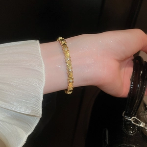 Detail of 18k gold iris bracelet with zircons worn on wrist with pleated sleeve
