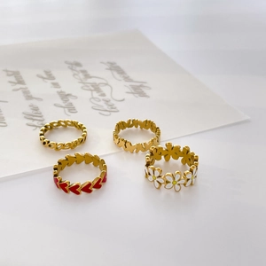 Close-up of four-piece gold ring set featuring red enamel heart and white daisy details