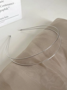 Detailed macro view of double-layer silver metal headband on champagne silk fabric