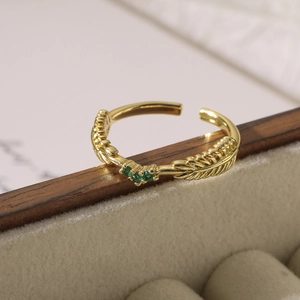 Vintage gold adjustable feather ring with three green zircon stones on jewelry box