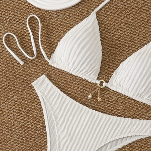 Detail of white textured bikini top with gold sea star and pearl charm decorations