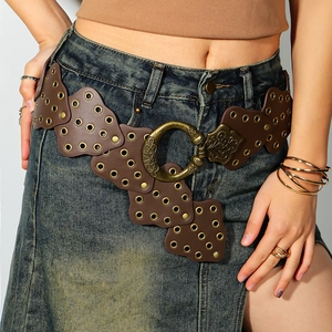 Dettaglio cintura in pelle marrone con occhielli metallici e fibbia in bronzo scolpita