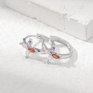 Silver hoop earrings with four multi-color marquise-cut zircons on a white textured stone