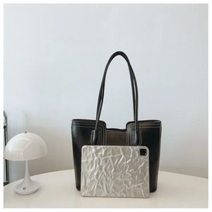 Detail of black leather tote bag with white stitching showing laptop capacity