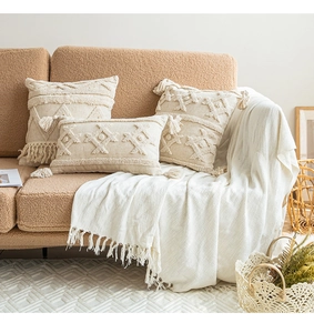 Macro detail of bohemian cream cushions with geometric embroidery and handmade tassels