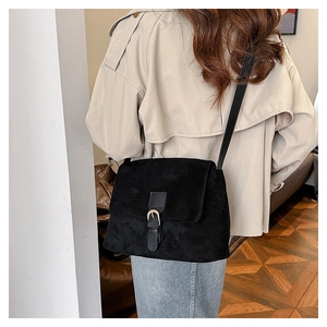 Back view of model wearing a black matte suede crossbody bag with khaki trench coat