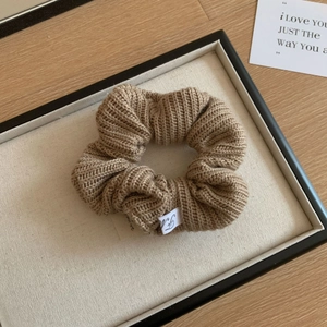 Vue détaillée du chouchou en tricot kaki avec texture côtelée et étiquette tissée