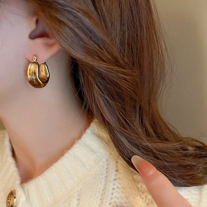 Close-up of vintage U-shaped resin amber hoop earrings worn by a model on side view