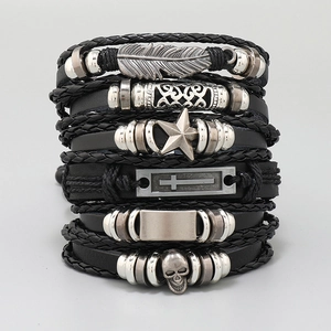 Detail of stacked braided leather bracelets with silver feather and skull charms