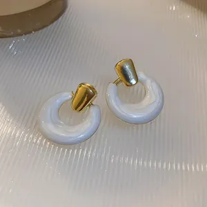 Macro shot of white marble texture C-shape earrings with elegant golden metal studs