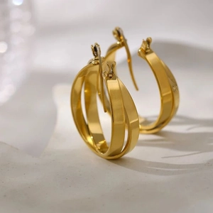Detail view of double-layered gold hoop earrings on white stone minimalist display