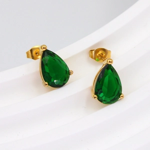 Macro shot of gold-plated pear-shaped earrings with emerald green teardrop stones