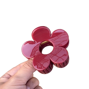 Pince à cheveux fleur rouge élégante avec boucle papillon tenue dans la main