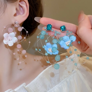Detail of long floral fringe earrings with fabric petals and sparkling blue resin crystals