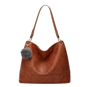 Detailed shot of brown faux leather tote bag with grey pompom and gold hardware