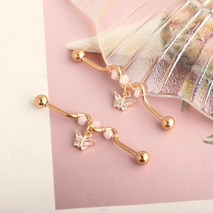 Macro shot of gold industrial barbell earrings with pink beads and butterfly charms