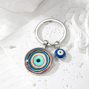 Detailed close-up of a blue Evil Eye glass pendant keychain on white textured stone background