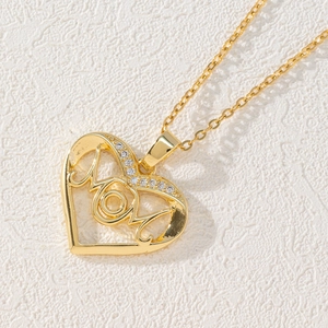Macro shot of gold heart-shaped pendant necklace with MOM lettering and zircon accents