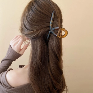 Detail view of large tortoiseshell hair claw clip securing a sleek brunette bun