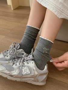 Details von dunkelgrauen Baumwollsocken mit weißem Spitzenrand und gestickten Schleifen