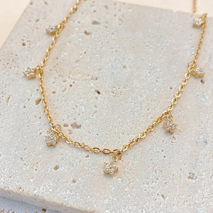 Close-up of gold stainless steel choker with small floral pendants inlaid with zircons