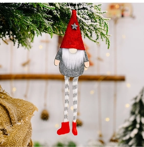 Handmade Christmas gnome plush with striped legs hanging on snowy pine branches