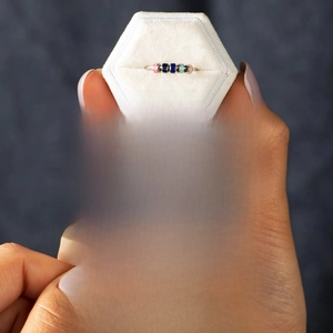 Macro detail of fidget ring with five colored beads in a white velvet gift box with card