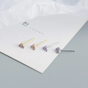 Macro shot of purple clover stud earrings in silver and gold finishes with triple crystals