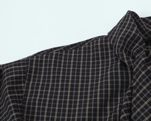 Detail view of cotton plaid shirt showing stitching and dark brown checkered fabric texture