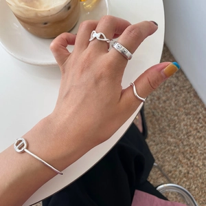 Detail of 925 sterling silver bear ring and link bracelet on hand over white coffee table