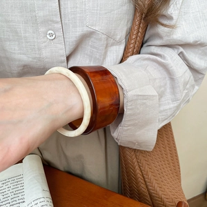 Stack of slim cream resin ring and wide amber tortoiseshell bangle on model wrist
