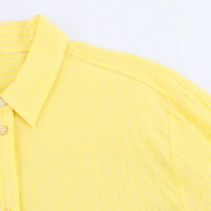 Dettaglio del tessuto in cotone a righe gialle con bottoni bianchi sulla camicia