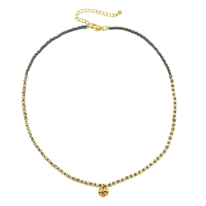 Macro detail of gold-plated hammered pendant on a minimalist beaded chain necklace