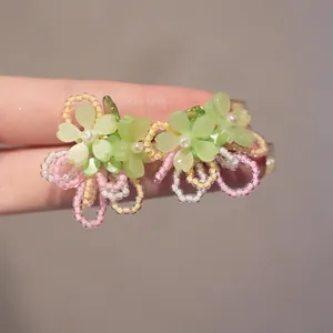 Detail of handmade resin flower hairpin featuring green petals and colorful beaded rings