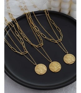 Close-up of double-layer gold angel coin necklace on a matte black display tray
