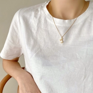 Close-up of a delicate 925 silver golden letter pendant necklace on a female model