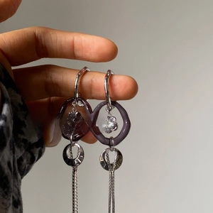 Detail of silver drop earrings with purple zircon hoops and long square chain tassels