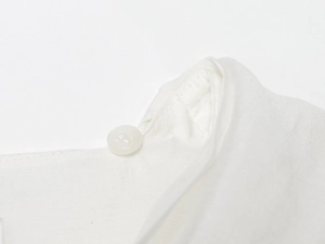 Macro view of a single translucent white button and fine stitching on a white blouse