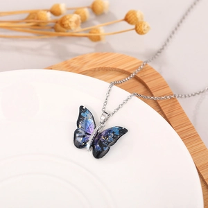 Macro shot of an acrylic butterfly pendant with blue-purple starry gradient on a silver chain