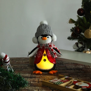 Detail of glowing penguin Christmas plush toy with warm LED light in soft fabric