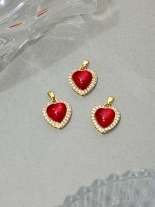 Macro shot of three red resin heart pendants with gold plating and white zircon inlay